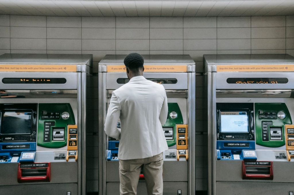 Business professional using a metro ticket machine at a transit station.